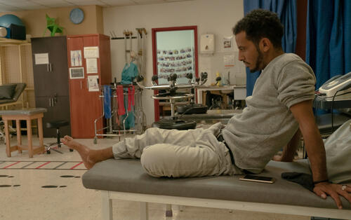  A man on a bed at the Amman Reconstructive Surgery Hospital, in the physiotherapy ward