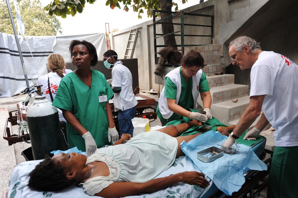 MSF staff treat a patient with two broken legs in a makeshift surgery area outside the Carrefour hospital in Haiti