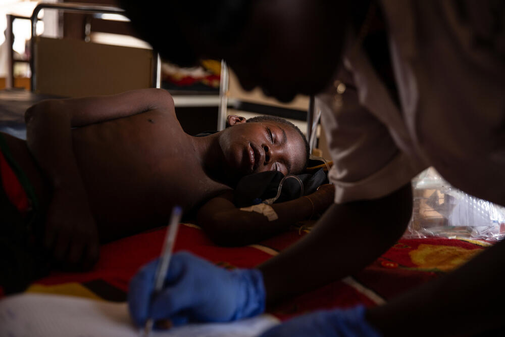 A nurse checks the temperature and condition of Maxime, who is being treated for measles with complications at the MSF-supported medical centre in Benzembe village.