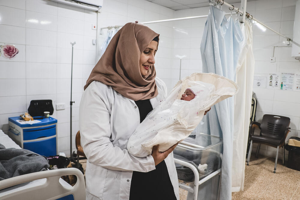 Midwife supervisor Rahma holding newborn Rivan at the Al-Amal maternity unit