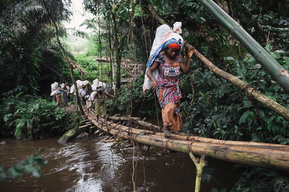 Porters carry sacks containing vaccination equipment over a bridge of bamboo and vines between the villages of Kitobo and Katanga during a vaccination campaign in Masisi territory, DRC.