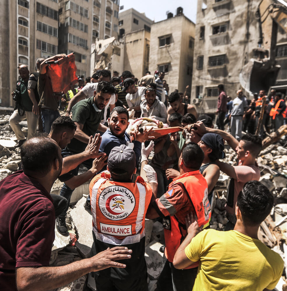 Palestinians rescue a person from a collapsed building after an Israeli air-strike destroyed a residential tower in Gaza City on 11 May 2021. 