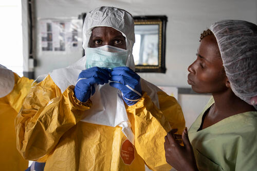 An MSF medic gets dressed into personal protective equipment before entering the high-risk zone of the Ebola Transit Centre in Bunia, Democratic Republic of Congo, 2019.