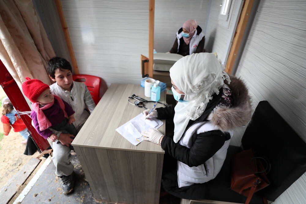 An MSF nurse talks with a young boy, who brought one of his relatives for a consultation at MSF’s mobile clinic in an IDP camp in northwest Syria.