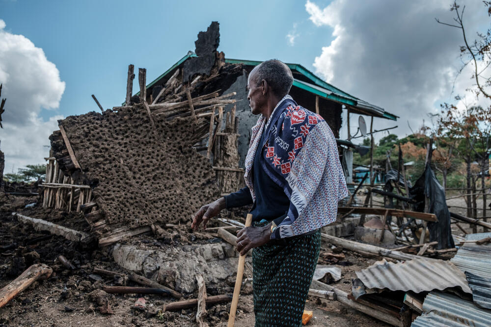 A man stands in front of his destroyed house in the village of Bisober, Ethiopia