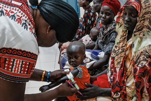Malnutrition screening of one-year-old Alnel on the knees of his mother Nyanbeny. Ameth Bek Hospital, Abyei.