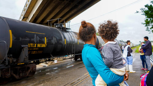 A woman holding a child next to a train