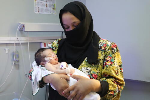 A mother holding her child in the MSF neonate intensive care unit at Abo Ali Sina Regional Hospital