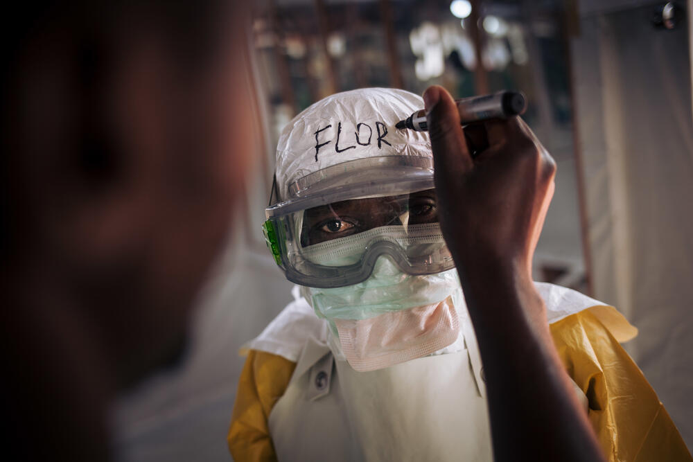 Health workers write their names on their personal protective equipment before entering the red zone, to make them more approachable to patients