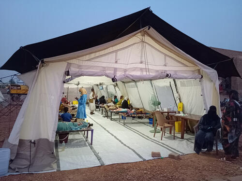 A cholera treatment centre consisting of a large tent with beds, patients and medical professionals