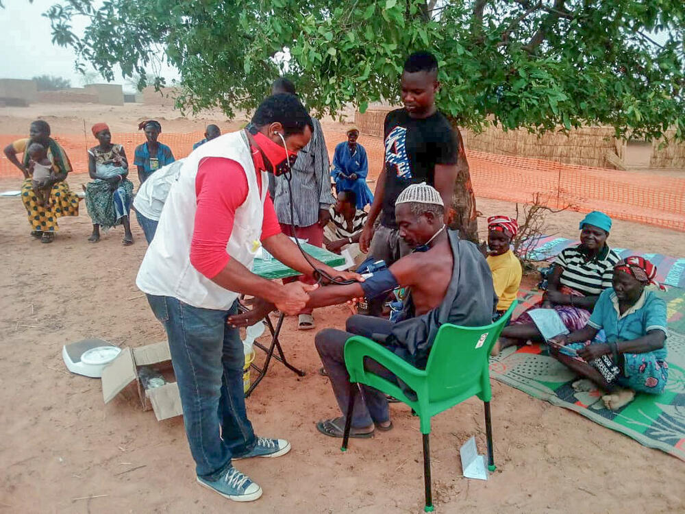 An MSF medic performs a health check on a group of displaced people