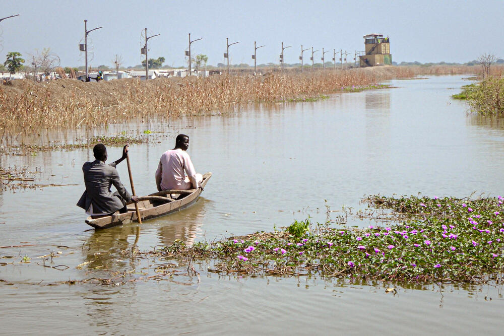 Two men use a canoe to navigate through floodwaters on the outskirts of Bentiu camp.