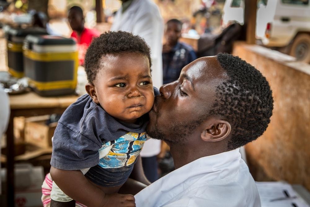 A care-giver kisses a child after their vaccination