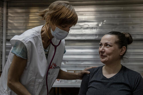 An MSF doctor checking on Alina, who has been sheltering in a station with her husband and mother for a month
