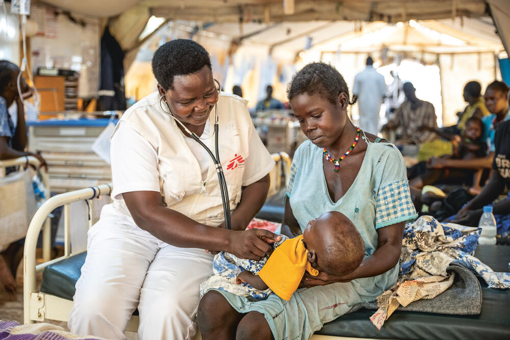 MSF nurse Scovia Morris examines a 13-month-old boy brought to Aweil Hosptial with his twin, both suffering from severe malnutrition