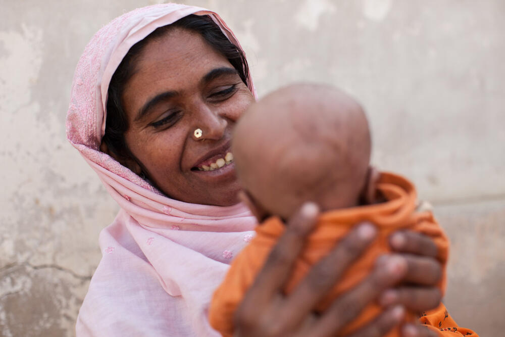 A woman smiles at her young baby at an MSF mobile clinic in Jaffarabad.