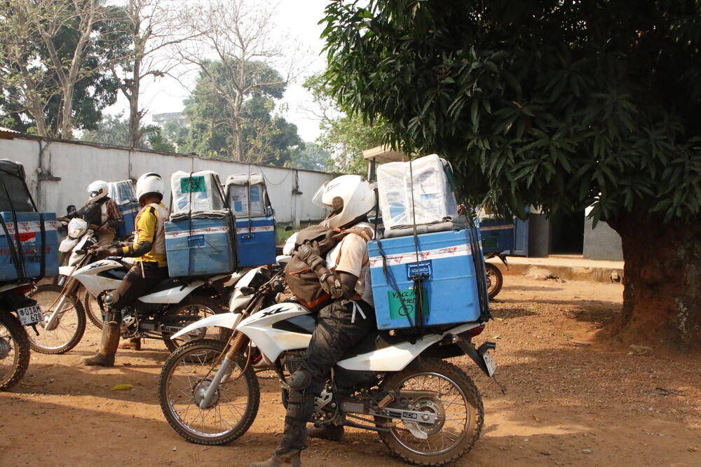 Cold chain equipment – needed to keep measles vaccines refrigerated – is loaded on motorcycles to be transported 180km to Bosobolo