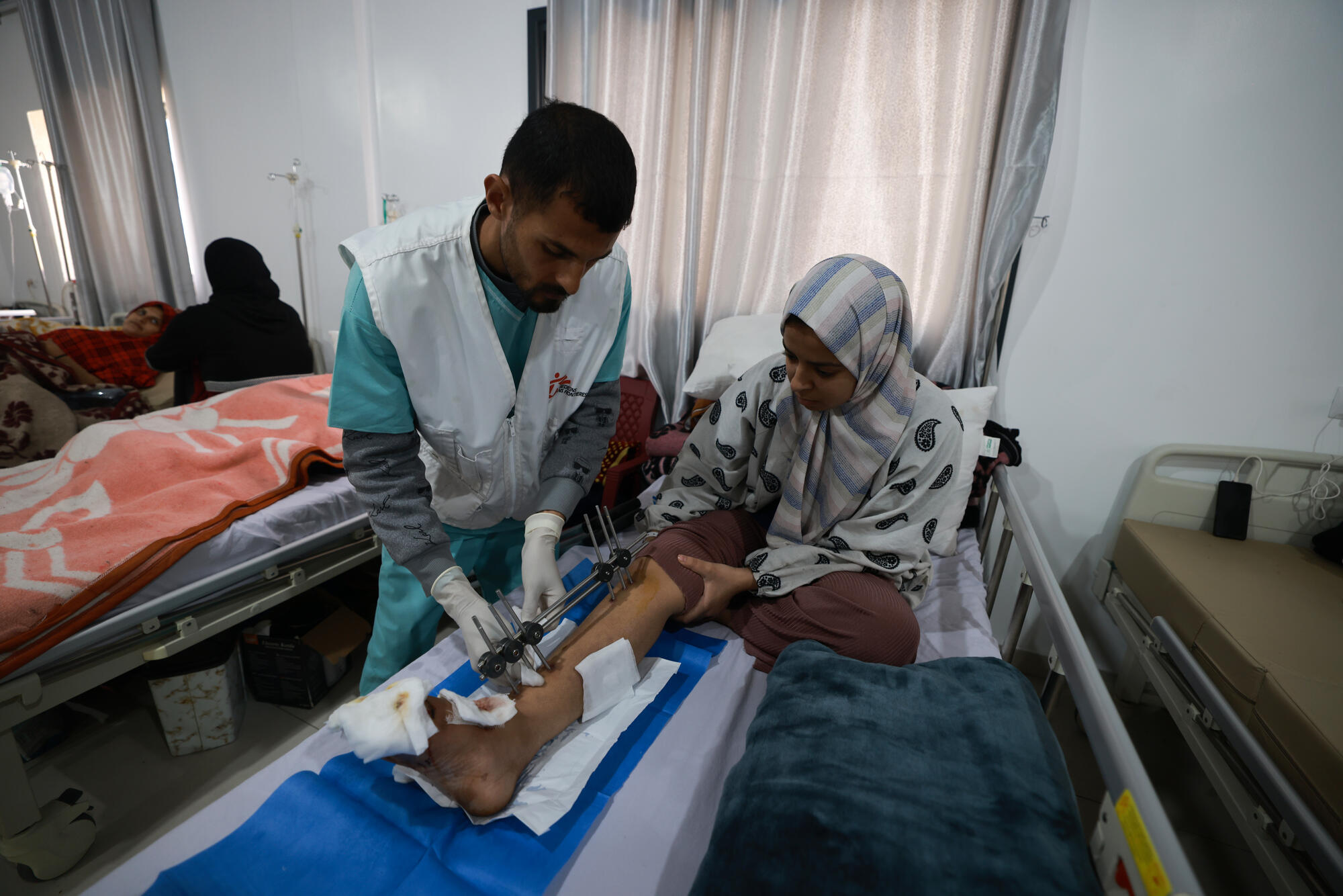 In Rafah, an MSF medic checks on a war-wounded patient who was forced to flee Al-Aqsa Hospital in Gaza's Middle Area