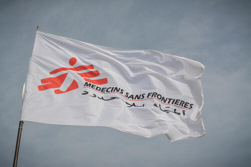 The MSF flag flutters in the wind above an MSF mobile clinic