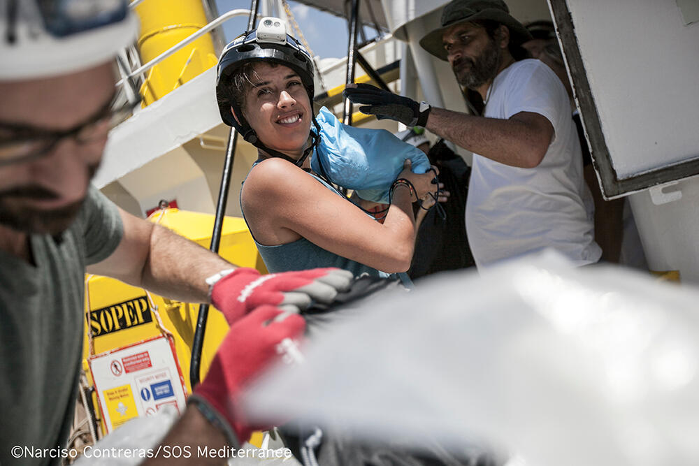 Alice helps to bring on board a delivery of new supplies to search and rescue ship Aquarius before it heads back to sea.