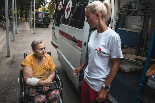 MSF feldsher helps a patient sit in the ambulance after a dialysis procedure