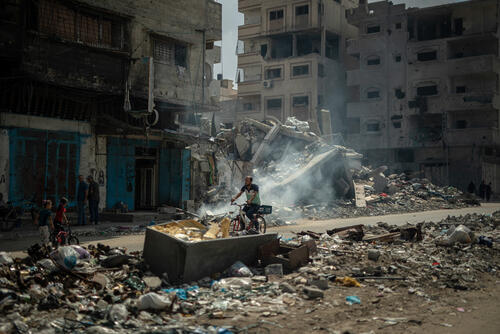 In Al Shate refugee camp in Gaza City, a man is riding his bicycle through the midst of the destruction