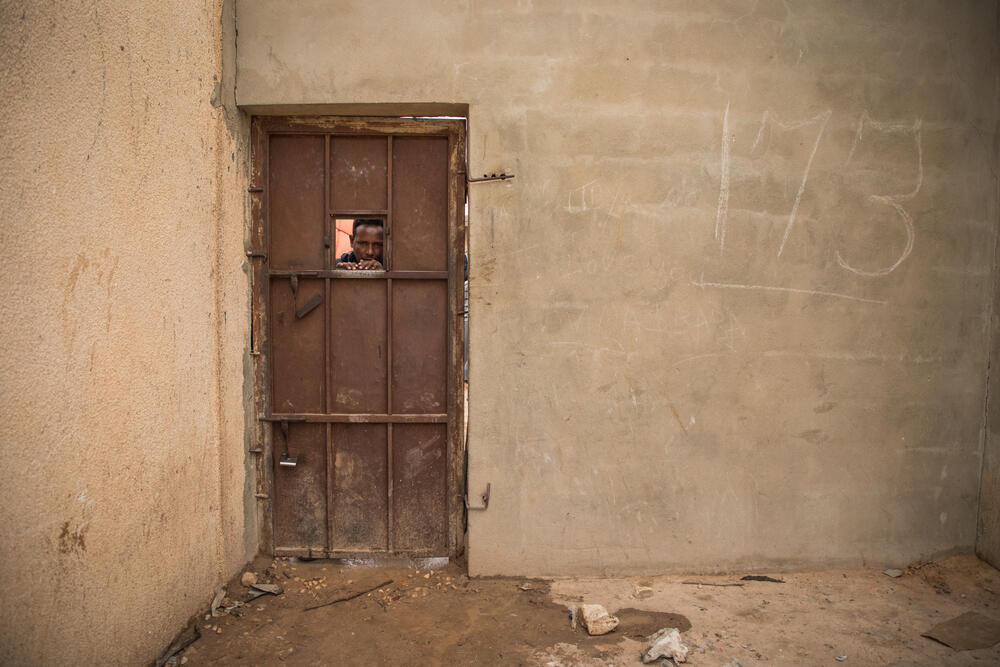 A man peers through a hole in a door in Dahr-el-Jebel detention centre, where nearly 500 people, most from Eritrea and Somalia, remain locked up. 