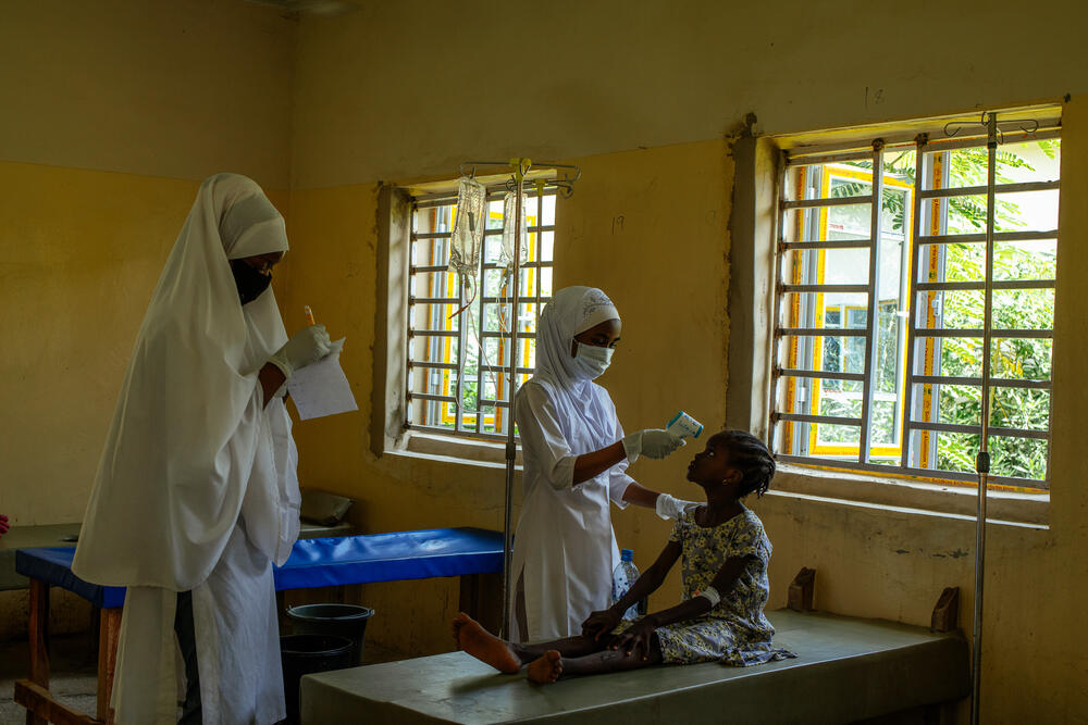 Bilkisu, an MSF nurse, checks the temperature of a young patient at the CTC in Kano