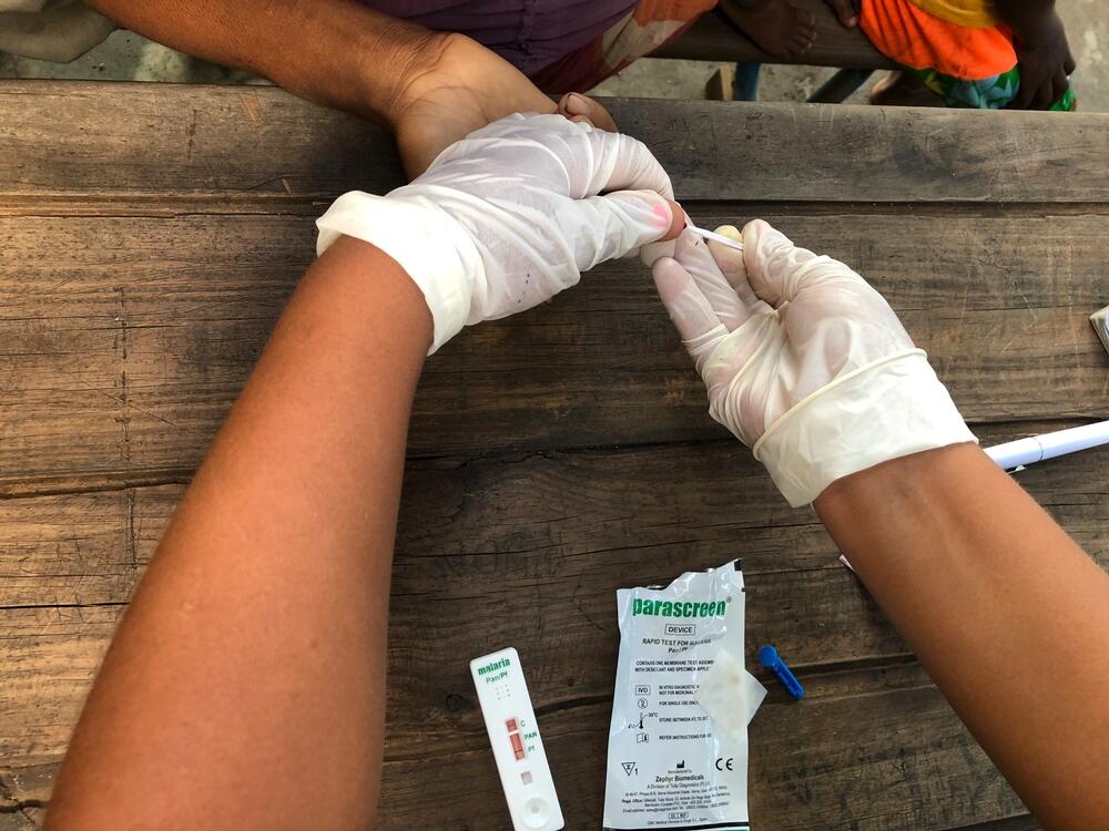 A patient receives a malaria test at an MSF mobile clinic taking place in a school