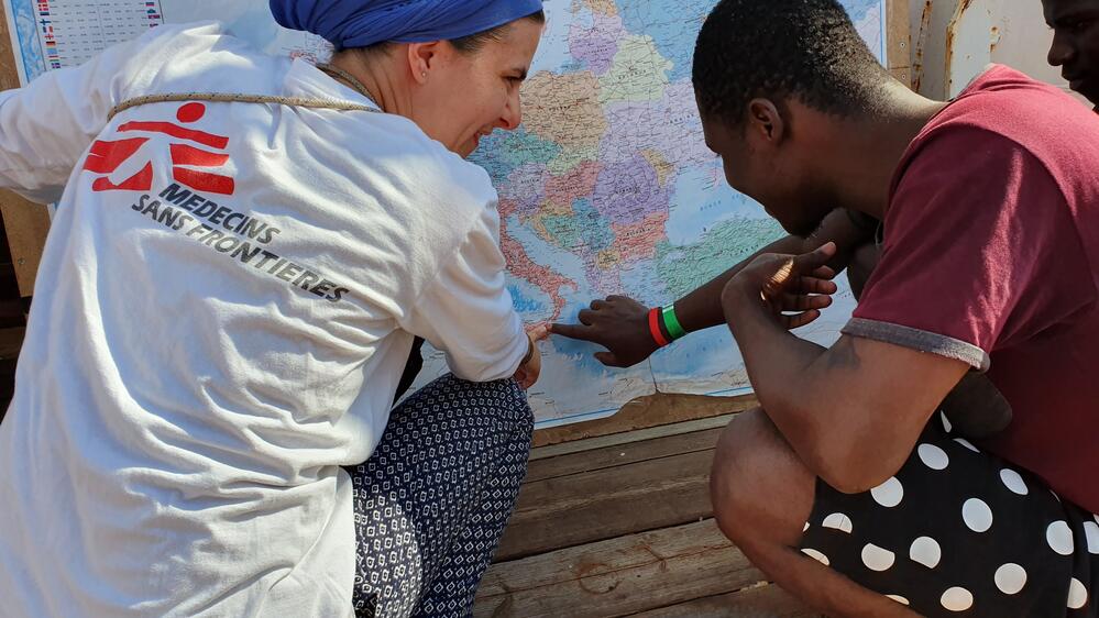MSF Medical Team Leader Stefanie looks at a world map with a rescued person on board the Ocean Viking
