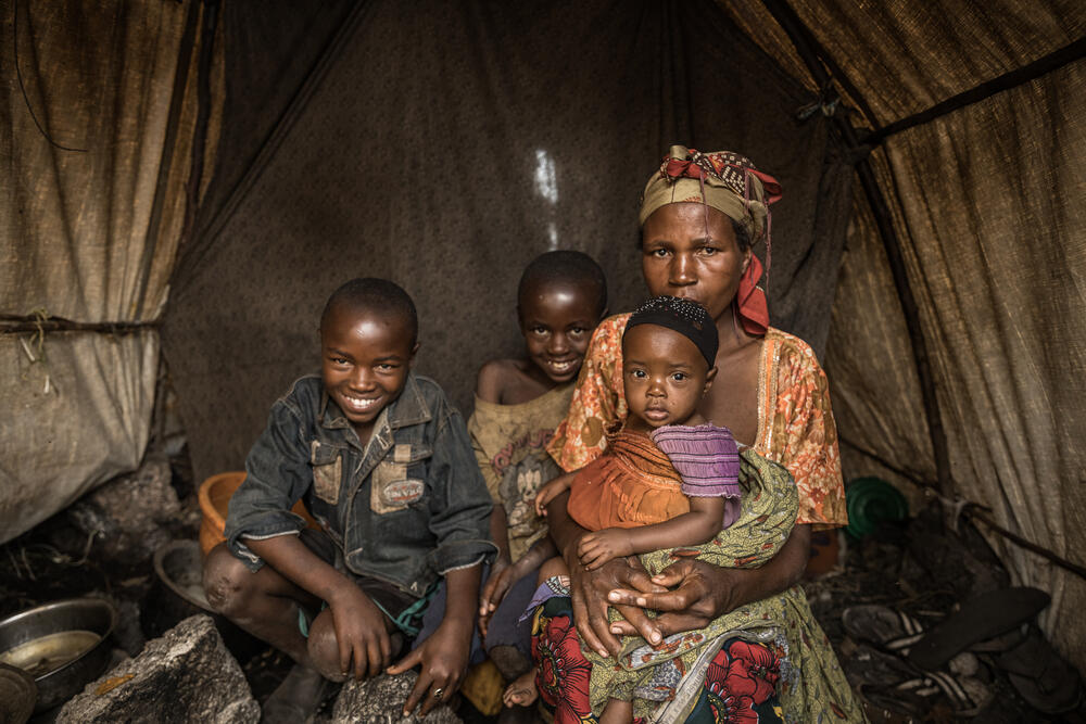 Foibe and her three children pose inside their tent. One of her children was recently treated by MSF for malnutrition and measles.
