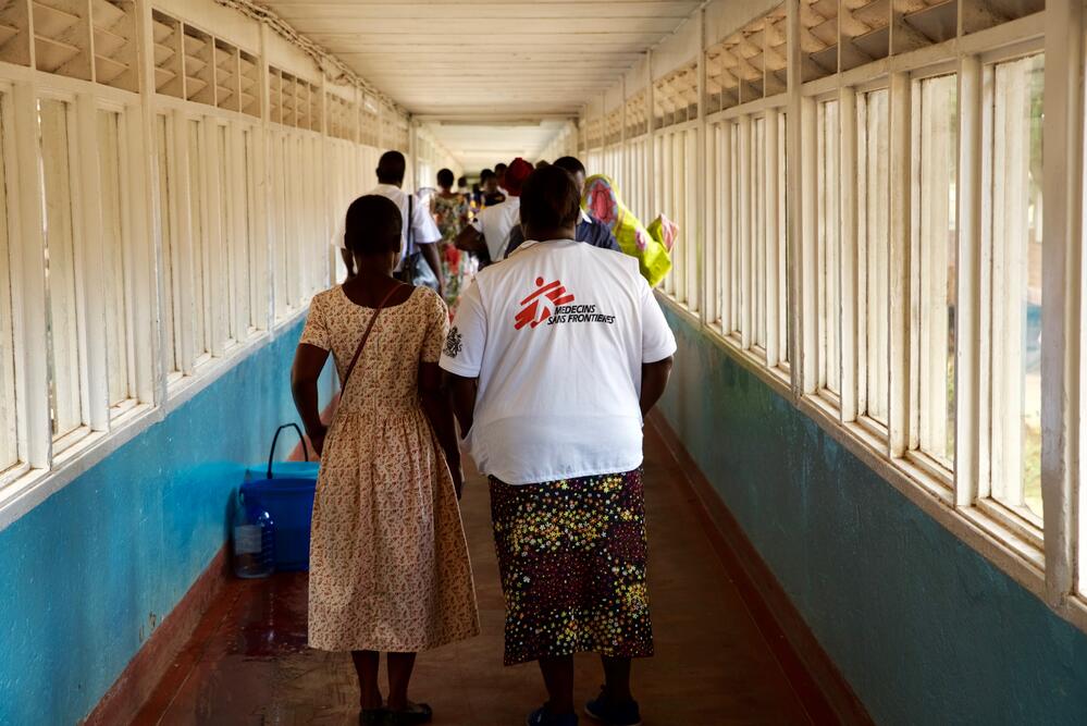 An MSF member of staff walks with a patient along the corridors of Queen Elizabeth Central Hospital in Blantyre, Malawi. March 2020. 