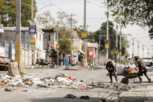 In Port-au-Prince, people cross a street with supplies following a clash between an armed group and police