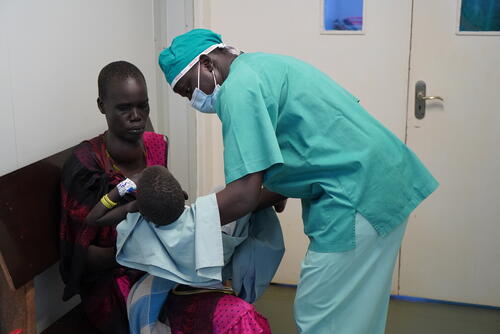 MSF anaesthetist William Deng hands four year old Cliudier back to her mother, after she has had her dressings changed in the operating theatre of the MSF hospital in Bentiu internally displaced persons camp. She has burns, her torso, legs and one arm from hot water. The MSF medical team will change her dressings regularly to ensure she doesn’t develop any infections.