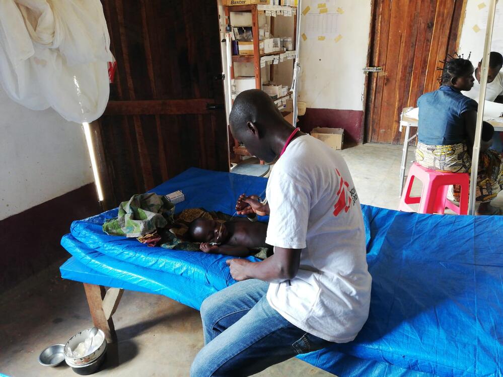 A staff member treats a young child suffering from measles and acute malnutrition in Mukanga.