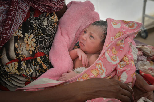 A newborn baby looks up at their mother at an MSF hospital in Sudan