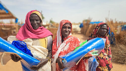 Scene of women receiving plastic sheeting in Aboutengué refugee camp