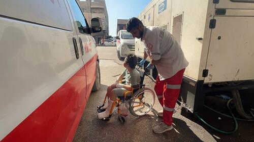 A little boy in a wheelchair is helped onto an ambulance A little boy in a wheelchair is helped onto an ambulance