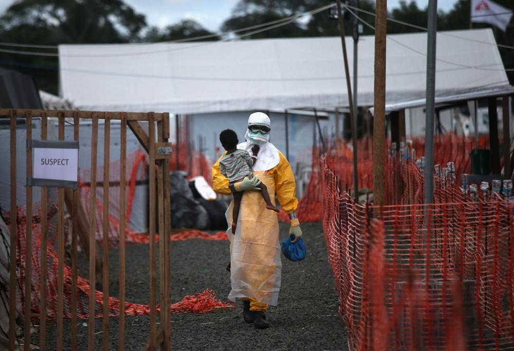An MSF health worker carries a child suspected of having Ebola in an MSF treatment centre in Paynesville, Liberia, 2014. 