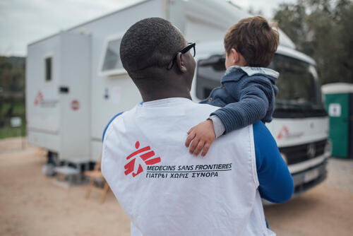 Dr. Yorpoi Bockarie holding a young patient in his arms.