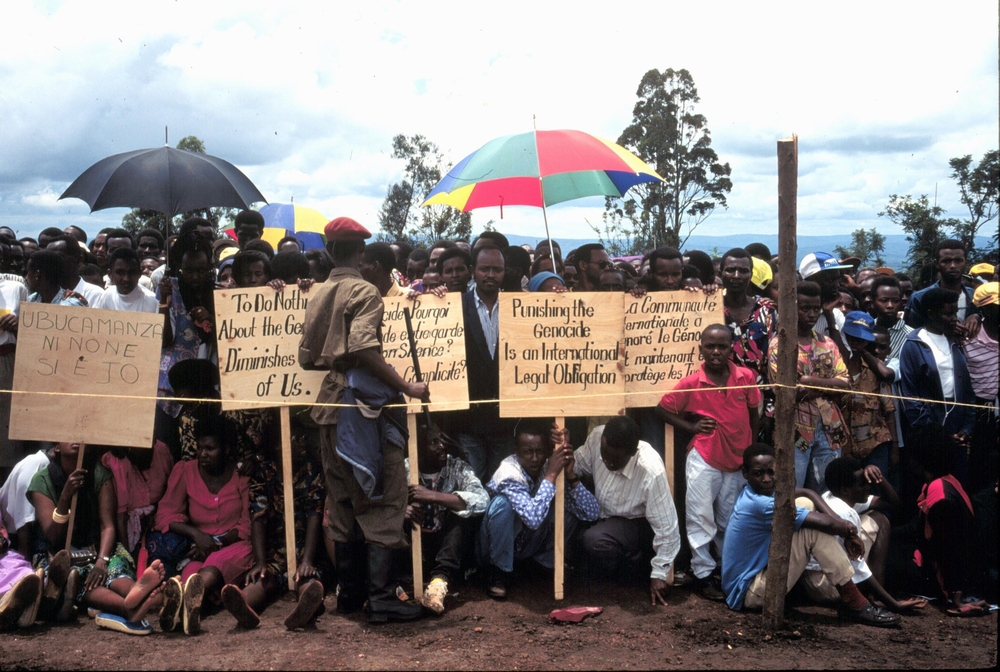 Tutsi survivors of the genocide at the one year anniversary of the genocide. Beneath umbrellas.