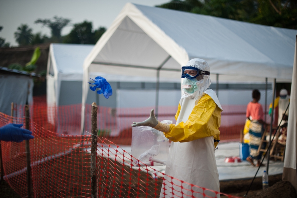 Člen Lékařů bez hranic vhazuje potřebné věci kolegovi v rizikové zóně ebolového centra, aby předešel kontaktu. © Peter Casaer