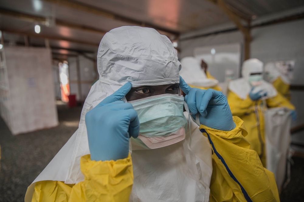 An MSF nurse checks her PPE in the mirror as she prepares to enter MSF